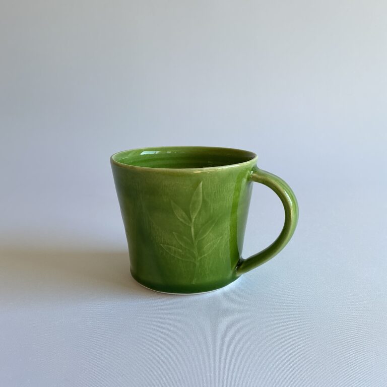Porcelain cup with bright green glaze and leaf design